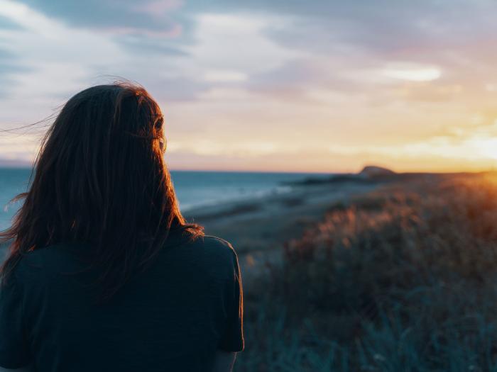 Woman watching the sunset on the coast